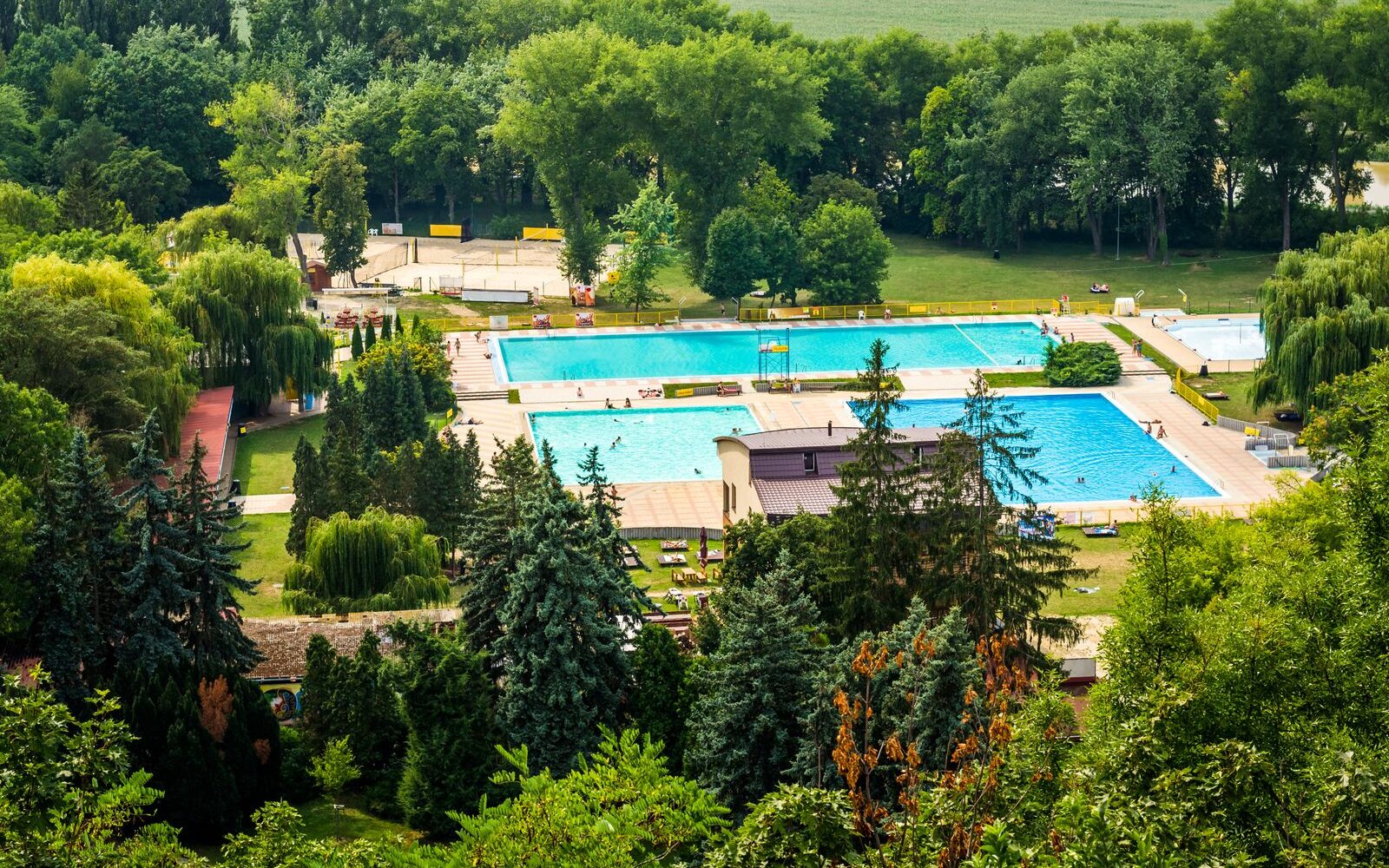 Venkovní bazény termálního koupaliště obklopené stromy