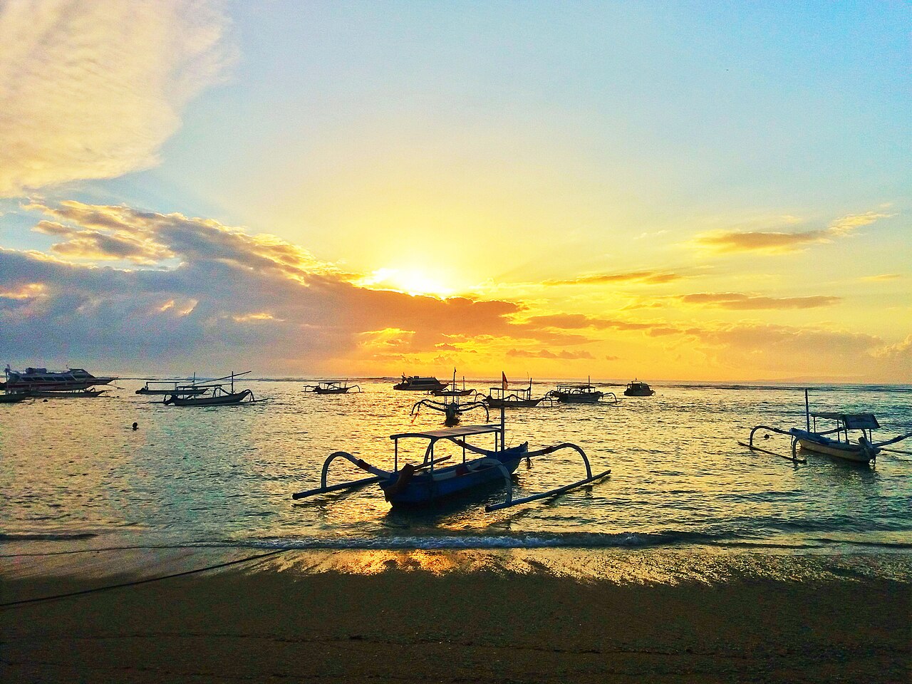 Ráno na pláži Sanur na Bali s tradiční lodí a klidnou hladinou